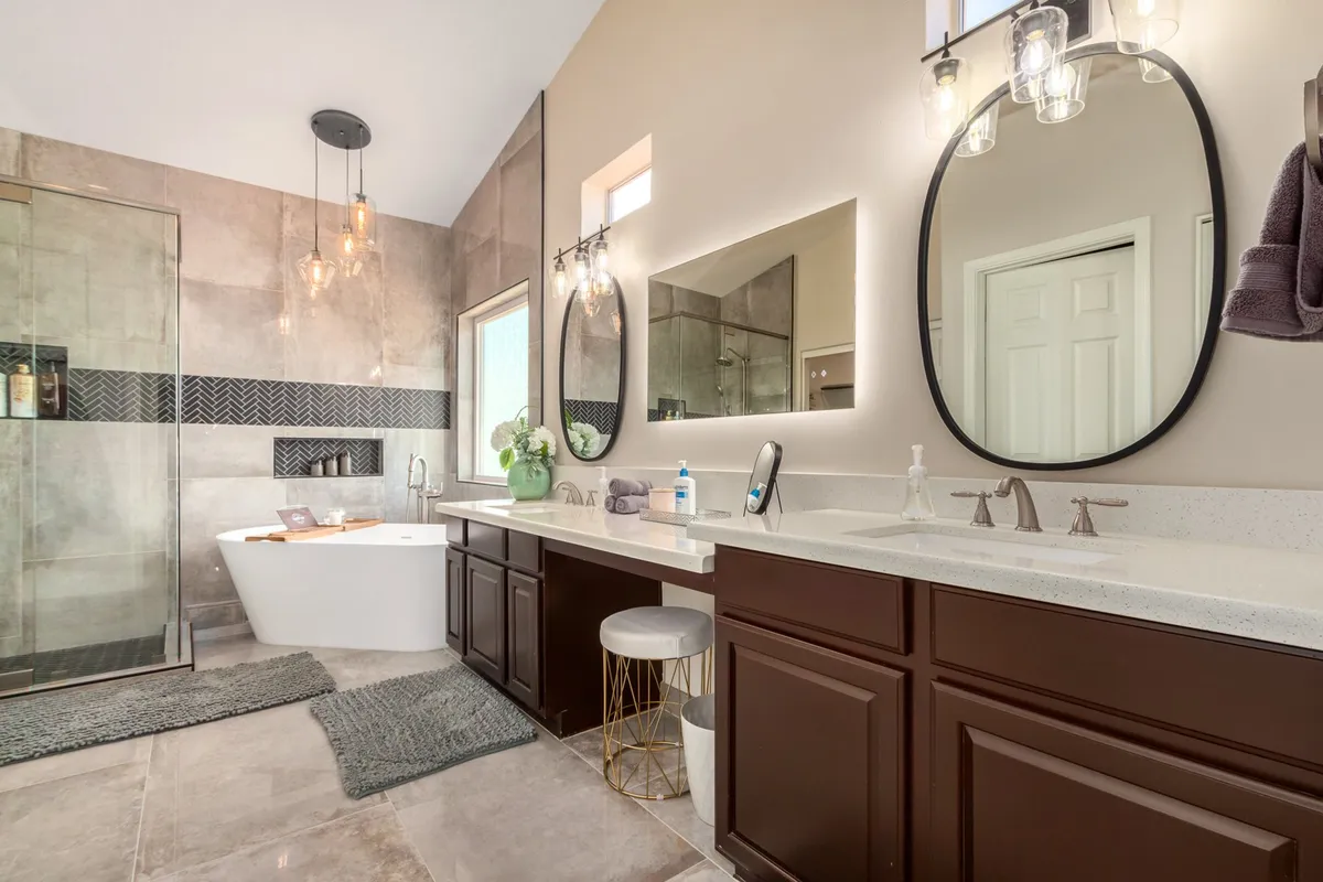 A spa-like bathroom with a freestanding bathtub, double sink vanity, large mirrors, glass shower enclosure, and elegant lighting fixtures. The ambiance is tranquil and luxurious, inviting guests to rejuvenate.