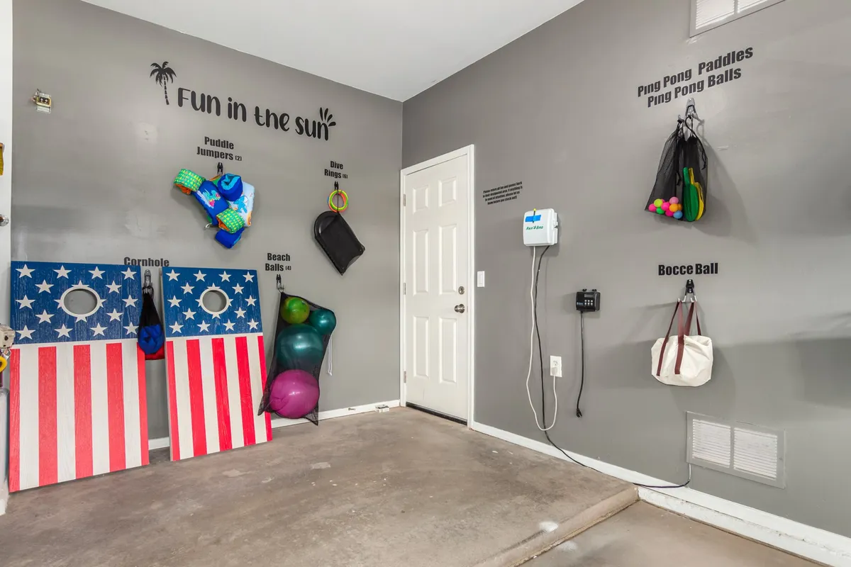 An energetic scene centered around colorful cornhole boards, pool toys like puddle jumpers and beach balls, and a group-friendly outdoor space designed for games and memorable moments. The mood is playful and inviting, encouraging friendly competition and group activities.