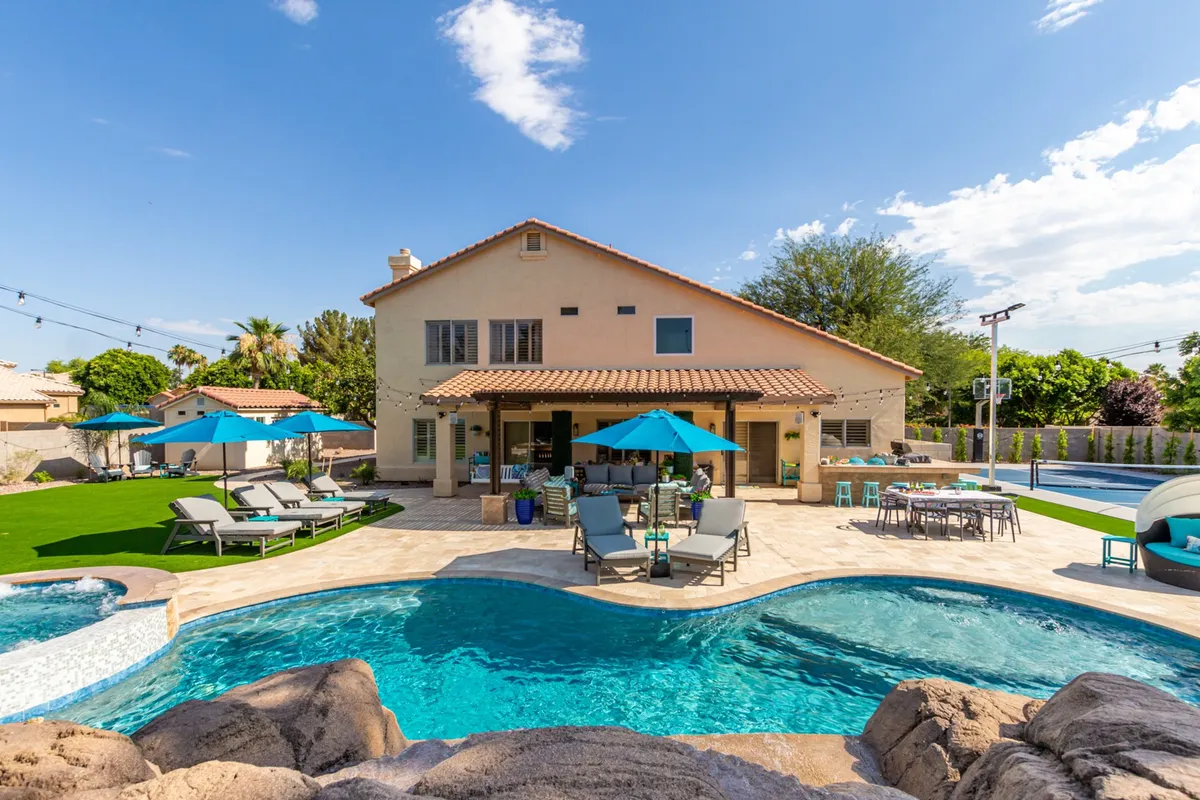 A spacious outdoor area featuring a sparkling swimming pool surrounded by a landscaped garden, with comfortable patio seating and a serene atmosphere. The scene is set during sunset, enhancing the relaxed mood and inviting guests to enjoy both swimming and socializing at any time of day.